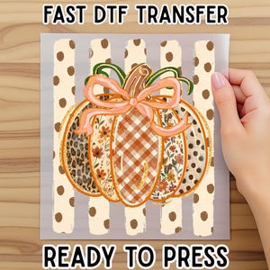 May include: A DTF transfer sheet featuring a pumpkin graphic with a peach-colored bow. The pumpkin has sections with leopard print, floral patterns, and orange gingham. The background has vertical cream stripes with brown polka dots. Text reads FAST DTF TRANSFER READY TO PRESS.