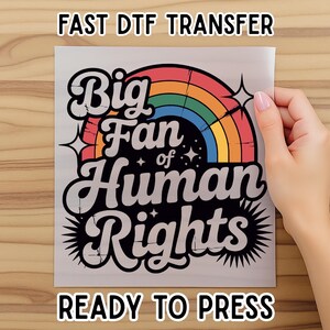 May include: A DTF transfer with the text "Big Fan of Human Rights" in a retro font, featuring a rainbow and starburst design. The words "Fast DTF Transfer" and "Ready to Press" are also displayed.