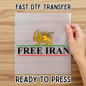 May include: A clear sheet with the text "FAST DTF TRANSFER" and "READY TO PRESS". The sheet features a gold lion emblem with a sword, the text "FREE IRAN", and green and red stripes.