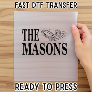 May include: A white transfer sheet with the text "THE MASONS" in bold black letters, along with two ring illustrations. The sheet also has the text "FAST DTF TRANSFER" and "READY TO PRESS" in black.