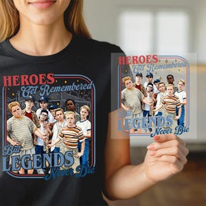 May include: Black t-shirt with a graphic of a group of boys and the text "HEROES Get Remembered But LEGENDS Never Die" in a retro style. The design includes a baseball field and a vintage aesthetic.