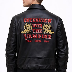 May include: Black leather jacket with the text "INTERVIEW WITH THE VAMPIRE" in red and gold embroidery on the back. The jacket features a classic bomber style with a ribbed hem and cuffs. The text includes "FILM CREW 1994".