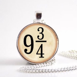 Peut inclure: Un collier pendentif argenté avec un charme circulaire affichant le nombre "9 3/4" en noir. Le charme a un fond crème et une bordure argentée. La chaîne est également argentée.