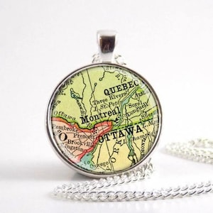 Peut inclure: Un collier pendentif rond en argent avec une carte vintage du Québec et d'Ottawa, Canada. La carte est dans des tons de vert, jaune et rouge, avec les noms des villes. Le pendentif est suspendu à une chaîne en argent.
