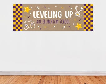 May include: A banner with the words "Leveling Up" and "ABC Elementary School" in white text. The banner has a brown background with yellow stars, a trophy, and a game controller. The banner's edges have a purple and yellow checkered pattern.