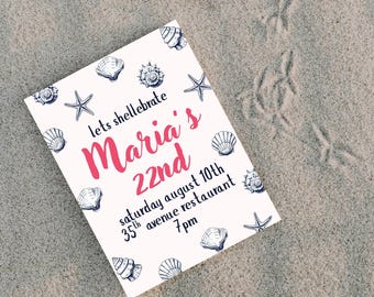 May include: A white invitation card with a beach theme, featuring seashells and starfish illustrations. The text reads "lets shellebrate Maria's 22nd" with event details. The card is on a sandy surface.