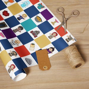 May include: A roll of colorful wrapping paper with a checkerboard pattern featuring cartoon characters and objects. A pair of scissors, a brown tag, and a spool of twine are on a wooden surface.