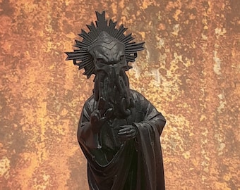 May include: Black painted figurine of a creature with tentacles wearing a robe and a halo. The creature has a human-like body and a head with a large, open mouth.