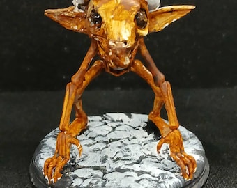 May include: A whimsical, hand-painted figurine of a creature with a Santa hat. The figure has a brown body, large ears, and is posed on a gray, textured base. The hat is red with a white trim, adding a festive touch.