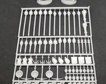 May include: A white plastic sprue sheet with various miniature accessories for tabletop gaming. The sheet includes swords, shields, torches, and other items. Two unpainted miniature figures are shown above the sprue sheet.