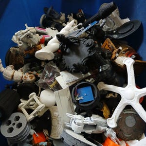 May include: A blue container filled with an assortment of 3D-printed miniatures and components. The collection includes white, grey, and black figures, along with architectural elements and mechanical parts. A diverse assortment of hobbyist and crafting supplies.