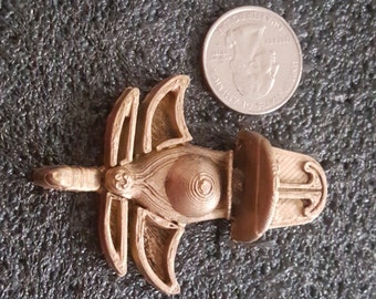 May include: A gold-colored metal pendant with a detailed design. The pendant features a circular center with a spiral pattern and two wings on either side. The pendant has a hook on the back for attaching to a chain.
