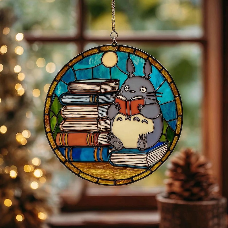 Puede incluir: Una vidriera redonda que representa un personaje de dibujos animados leyendo un libro mientras est&aacute; sentado en una pila de libros. La ventana tiene un borde azul y amarillo y cuelga de una cadena.
