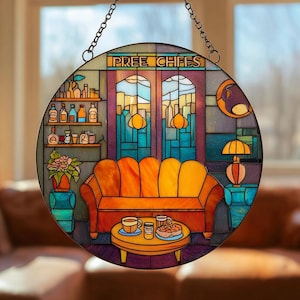 May include: A circular stained glass window depicting a coffee shop interior. It features a yellow sofa, a table with coffee and pastries, and a cityscape visible through the window. The text "PREE CHIFES" is at the top.
