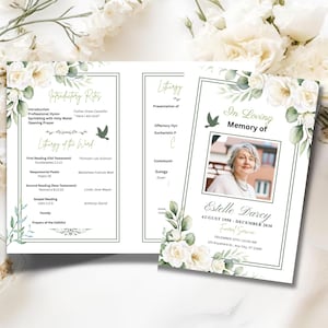 May include: A tri-fold funeral program with a floral design. The program includes the text "In Loving Memory of Estelle Darcy" and details of the funeral service. The design features white roses and green foliage, with a photo of the deceased.