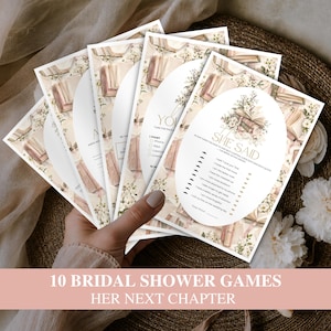 May include: A stack of printed bridal shower game cards featuring a floral and vintage book illustration. The top card displays the text 'HE SAID SHE SAID' with a list of statements and checkboxes for guests to guess who said each quote, set against a white oval.
