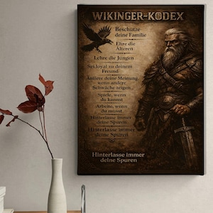 Könnte beinhalten: Leinwanddruck mit einer Illustration eines Wikingerkriegers, einem Raben und deutschem Text. Der Text enthält Sätze wie "Schütze deine Familie" und "Hinterlasse immer deine Spuren". Das Kunstwerk hat ein Vintage-Aussehen.