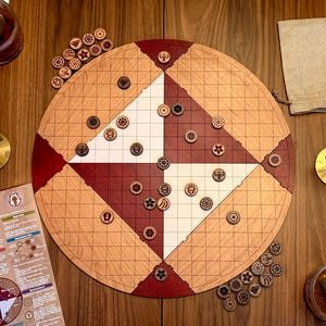 May include: A wooden Shud Pai Sho board game with red, white, and natural wood tones. The circular board features a grid pattern and is surrounded by wooden game pieces. A linen bag, tea, and candles are also present.