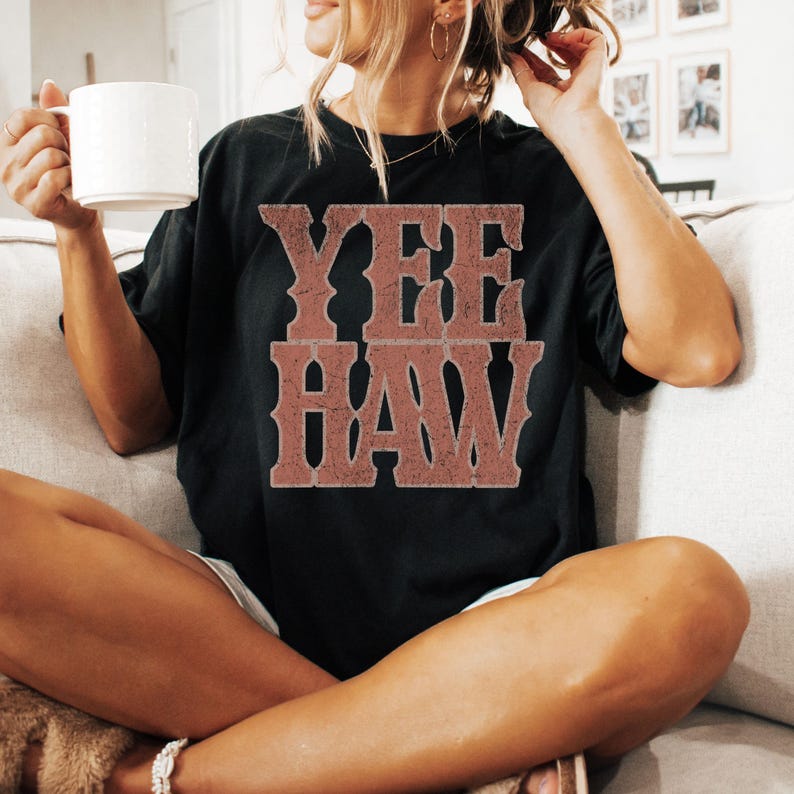 Pu&ograve; includere: T-shirt nero con la scritta "YEE HAW" in un carattere rosso-marrone usurato. La maglietta &egrave; di stile casual, adatta all'uso quotidiano. Il design ha un'estetica vintage di ispirazione western.
