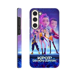 Peut inclure: Coque de téléphone avec un graphisme vibrant de trois personnages féminins animés vêtus de tenues violettes, jaunes et oranges. L'étui a un fond bleu et violet avec le texte "KPOP DEMON HUNTERS". Le côté de l'étui est violet.