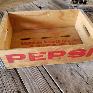 May include: Vintage wooden crate with metal accents, featuring the Pepsi logo in red lettering. The crate is labeled "Southern Wooden Box, Inc. 10 Jonesboro, Ark. B3."