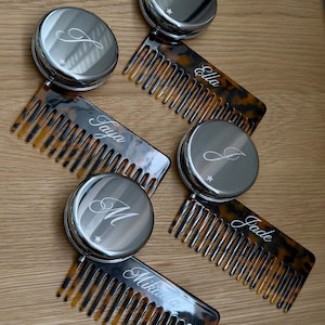 May include: Four sets of round silver-toned compact mirrors paired with tortoise-shell patterned hair combs. Each mirror is engraved with a single letter and a small star, while each comb features a custom name in white script lettering.