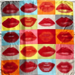 May include: A square silk scarf with a grid of red lips against a colourful background. The lips are in a pop art style, with a halftone dot effect. The background colours include grey, yellow, orange, and red.