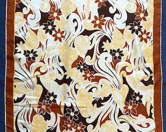 Könnte beinhalten: Quadratisches Tuch mit floralem Muster in Braun-, Creme- und Gelbtönen. Das Design zeigt stilisierte Blumen und Blätter vor cremefarbenem Hintergrund, umrahmt von einem braunen Rand mit weißem Besatz.