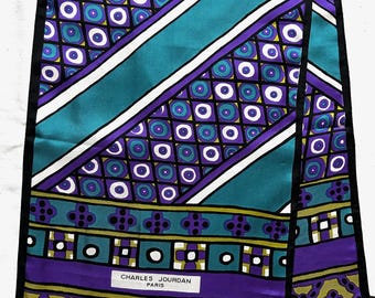 May include: A vintage silk scarf with a vibrant geometric pattern in teal, purple, white, and black. The scarf features diagonal stripes and repeating circular and square designs. The text "CHARLES JOURDAN PARIS" is visible.