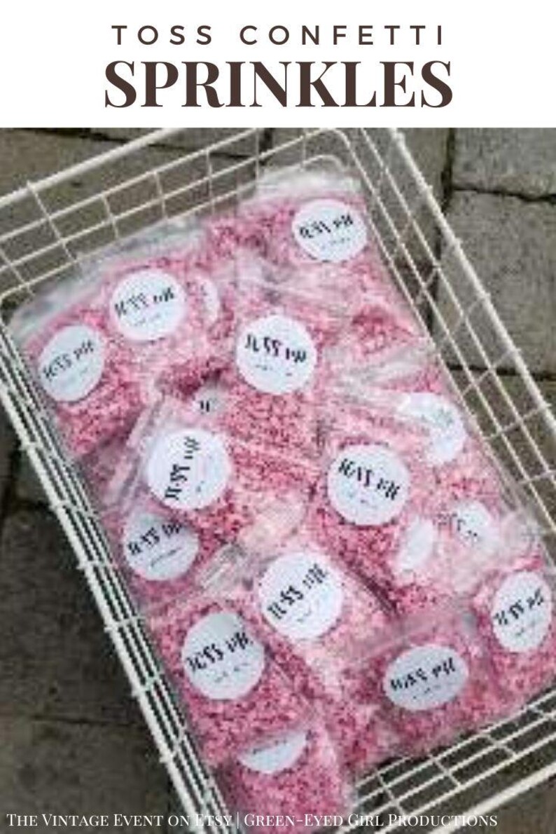 Puede incluir: Una cesta de alambre blanca llena de peque&ntilde;as bolsas de confeti rosa. Cada bolsa tiene una pegatina circular blanca con el texto "Toss Confetti" impreso en ella.