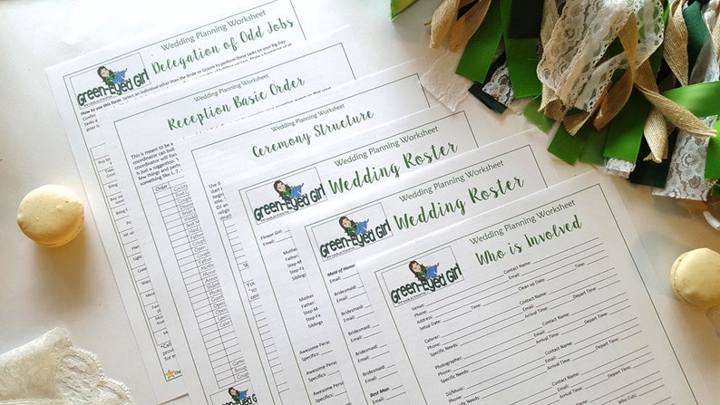 May include: A collection of wedding planning worksheets with headings like "Delegation of Odd Jobs" and "Wedding Roster." The worksheets are printed on white paper with green accents and the "Green-Eyed Girl" logo. Decorative ribbons and a macaron are also visible.