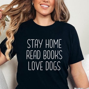 May include: A black t-shirt with the text "Stay Home Read Books Love Dogs" in white lettering.