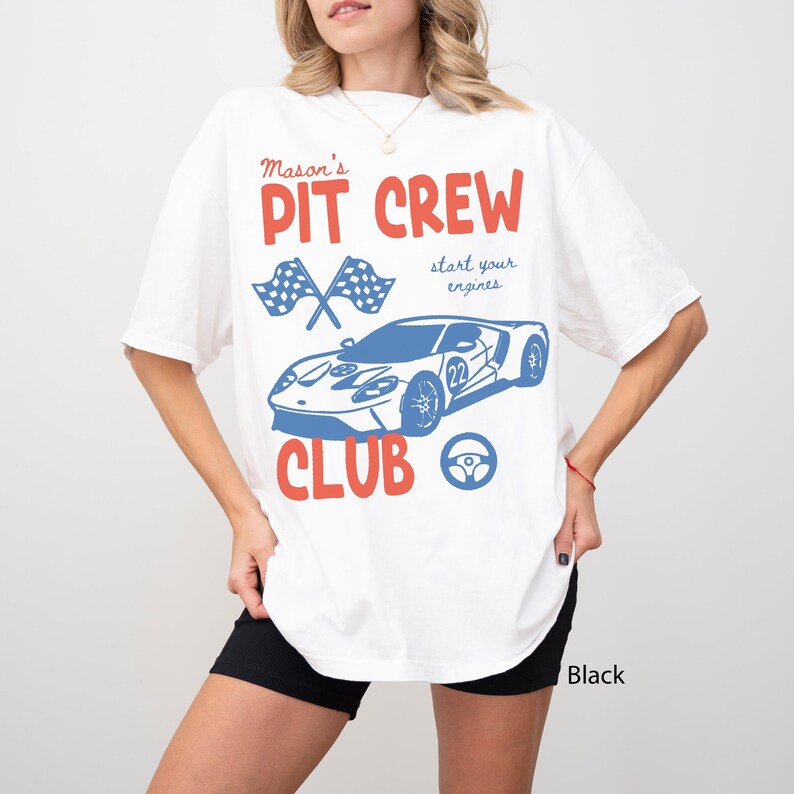 May include: White t-shirt with a red and blue graphic. The design includes the words "Mason's PIT CREW CLUB" with a blue race car, checkered flags, and a steering wheel. The phrase "start your engines" is also included.