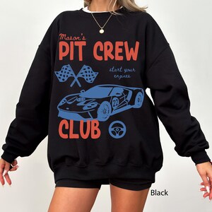 May include: Black sweatshirt with the text "Mason's PIT CREW CLUB" in red and blue. The design includes a race car, checkered flags, and a steering wheel. The words "start your engines" are also included.