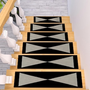 May include: A set of six rectangular stair treads featuring a black background with a central light gray geometric bowtie pattern. The treads are arranged sequentially on wooden stairs next to a white railing with decorative balusters.