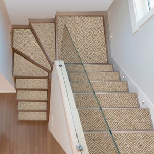 May include: Staircase with beige woven carpet treads and risers. The carpet has a geometric pattern. The stairs have wooden frames and a glass railing. The walls are white, and the flooring is light wood.