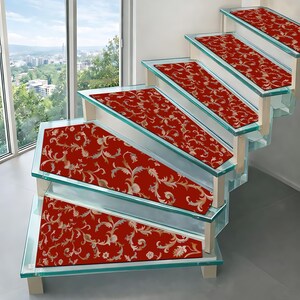 Puede incluir: Peldaños de escalera con un patrón floral rojo y dorado. Están instalados en una escalera de vidrio, con vistas a una ciudad a través de una gran ventana. Los peldaños añaden un elemento decorativo.
