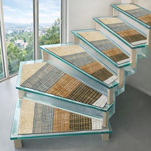 Op de afbeelding: Een set rechthoekige trapmatten met een geometrisch ruitpatroon in tinten beige, antracietgrijs en mosterdgeel. Elke mat ligt op een trede van helder glas, wat zorgt voor een consistent en gestructureerd ontwerp over de gehele trap.