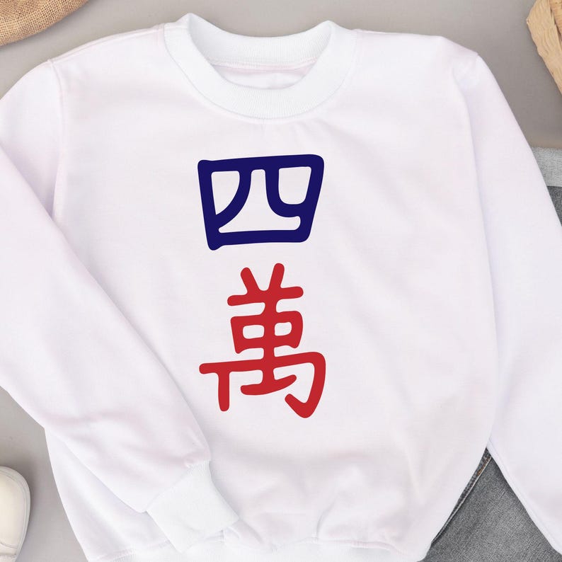 May include: White crewneck sweatshirt with the Chinese characters for "four ten thousand" in blue and red. The characters are vertically aligned on the front of the sweatshirt. The sweatshirt is made of a soft material.
