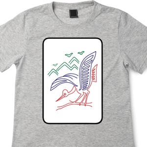 May include: A light gray t-shirt featuring a rectangular graphic with a bird design. The bird is depicted with red, blue, and white outlines, with green mountains and birds in the background. The shirt has a crew neck.