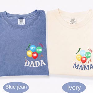 Pu&ograve; includere: Una t-shirt color blu jeans e una t-shirt color avorio, entrambe con una grafica di palloncini e stelle filanti colorate. La maglia blu riporta la scritta "IT'S FUN TO BE DADA" e quella avorio la scritta "IT'S FUN TO BE MAMA" in bianco.