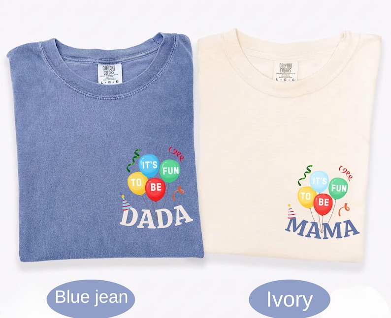 Pu&ograve; includere: Una t-shirt color blu jeans e una t-shirt color avorio, entrambe con una grafica di palloncini e stelle filanti colorate. La maglia blu riporta la scritta "IT'S FUN TO BE DADA" e quella avorio la scritta "IT'S FUN TO BE MAMA" in bianco.
