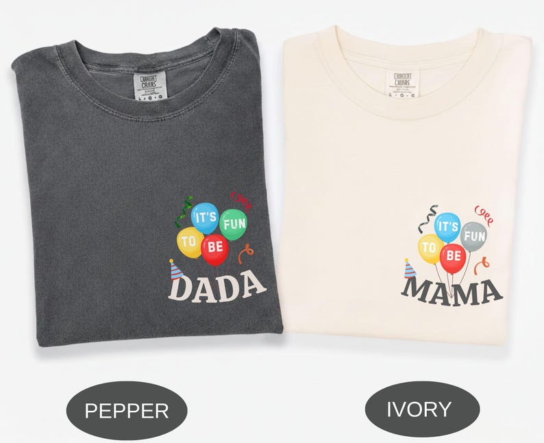 Pu&ograve; includere: Una t-shirt color pepe e una t-shirt color avorio, entrambe con una grafica di palloncini colorati con il testo 'IT'S FUN TO BE DADA' sulla maglia color pepe e 'IT'S FUN TO BE MAMA' su quella avorio, accompagnate da festoni e un cappellino.