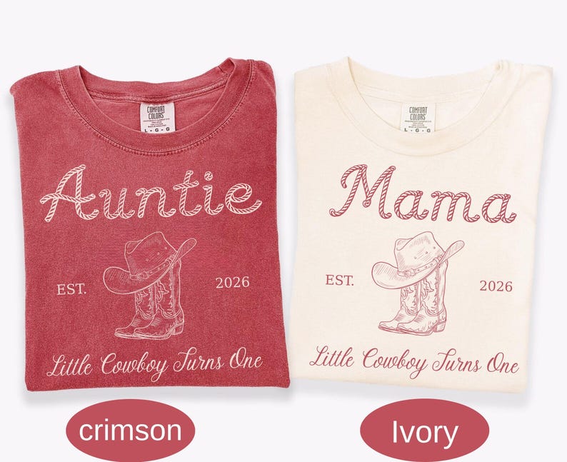 May include: Two short-sleeve t-shirts in crimson and ivory. The crimson shirt features white text reading Auntie, EST. 2026, and Little Cowboy Turns One with a cowboy hat and boots graphic. The ivory shirt features matching maroon text and graphics.