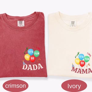 Pu&ograve; includere: Una t-shirt color cremisi e una color avorio, entrambe con una grafica di palloncini colorati con il testo 'IT'S FUN TO BE' e 'DADA' o 'MAMA' stampato sotto. Le magliette hanno un girocollo e un'etichetta del marchio Comfort Colors.