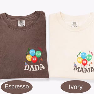 Pu&ograve; includere: Una t-shirt marrone espresso e una t-shirt color avorio, entrambe con una grafica di palloncini colorati con il testo IT'S FUN TO BE DADA sulla maglia marrone e IT'S FUN TO BE MAMA su quella avorio, con cappellini da festa e stelle filanti.