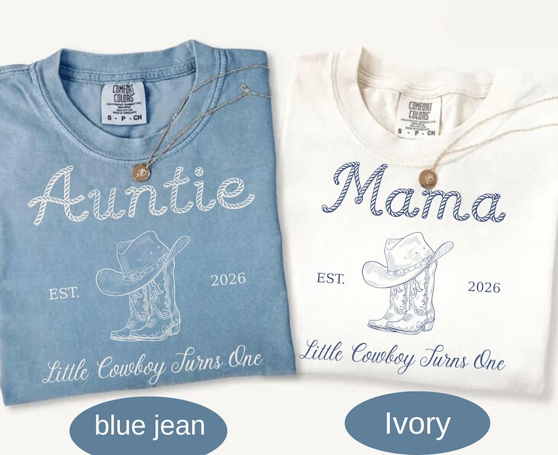 May include: A blue jean and an ivory t-shirt, each featuring a graphic of a cowboy hat and boots. The blue shirt displays the text Auntie, while the ivory shirt displays Mama. Both shirts include the text EST. 2026 and Little Cowboy Turns One.