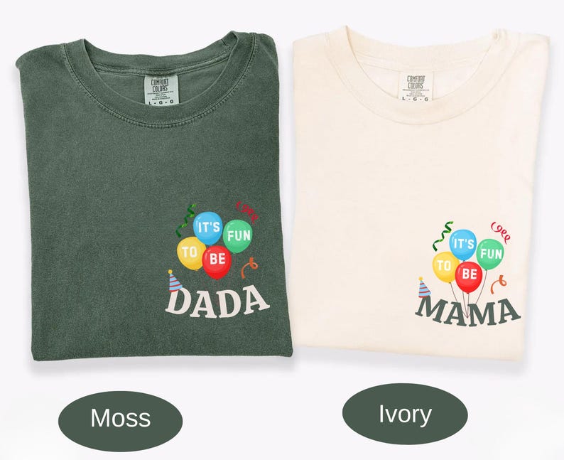 Pu&ograve; includere: Una t-shirt verde muschio e una t-shirt color avorio, entrambe con una grafica di palloncini e stelle filanti colorate. La maglia verde riporta la scritta "IT'S FUN TO BE DADA" e quella avorio "IT'S FUN TO BE MAMA" in bianco e grigio scuro.