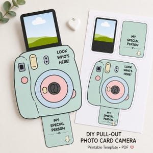 May include: A DIY pull-out photo card camera craft project featuring a light green instant camera with a pink lens and a pull-out tab that reads MY SPECIAL PERSON. The design includes a photo insert showing a landscape and the text LOOK WHO'S HERE.