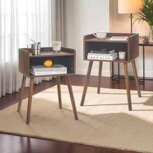 May include: Two wooden nightstands with a dark brown finish. Each nightstand has a top surface, an open shelf, and angled legs. The nightstands are in a room with a rug, curtains, and a lamp.